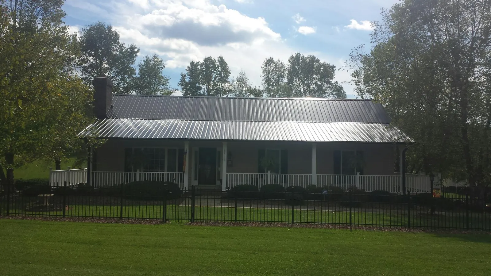 Gray metal roof on a brick ranch with a full width front porch in Camden